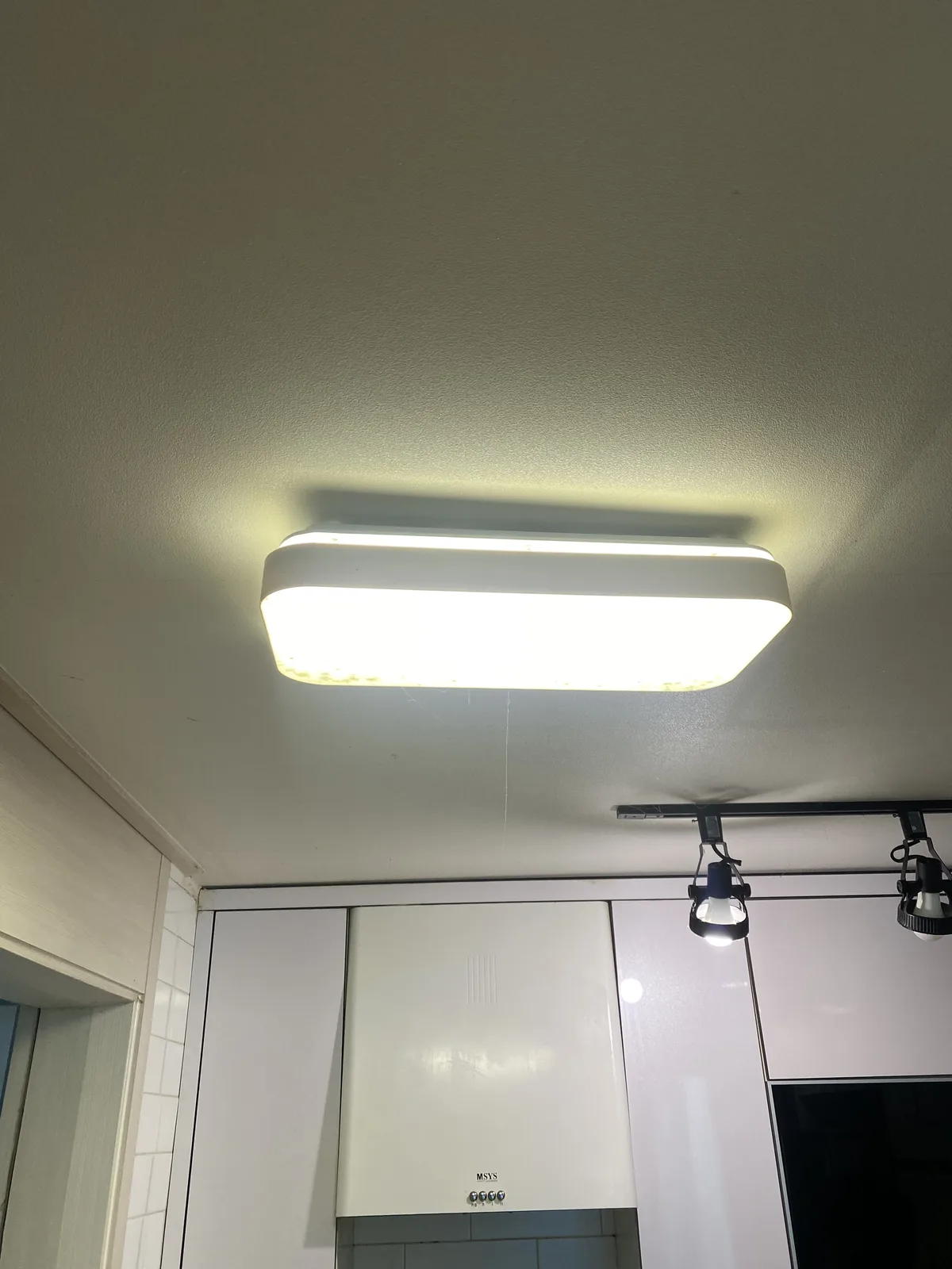 레일 조명과 상부 수납장이 설치된 주방 공간